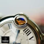 Cartier Ballon Bleu Two-Tone Watch Crown Detail, featuring an 18K gold setting with a blue cabochon, resembling a floating blue balloon.