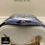 Replica Rolex Oyster Perpetual Blue Date m124300 watch side view, showcasing the intricate details of the Oystersteel case and the prominent crown.