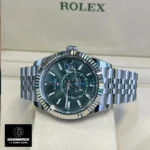 The replica Rolex Sky Dweller green dial watch stands on its side in the watch box, highlighting its appearance.