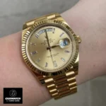 Replica Rolex Day Date Yellow Gold M228238 Watch worn on the wrist, exuding luxury and refinement with its signature yellow gold case.