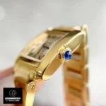 Close-up of watch dupe craftsmanship - Cartier Tank-style 18K gold case with signature blue synthetic sapphire cabochon crown replica