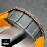 A side‑profile close‑up of the Richard Mille RM 11‑01 McLaren collaboration, featuring a multi‑layer Carbon TPT case interwoven with orange Quartz TPT