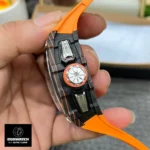 Close‑up of the crown and Flyback pusher on the Richard Mille RM 11‑03 McLaren: the titanium crown replicates McLaren’s lightweight steering wheel design, while the Flyback button echoes the 720S headlight motif.