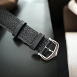 Interchangeable black grained calfskin strap with polished stainless steel pin buckle for Cartier Tank Must WSTA0042, ensuring secure and adjustable fit.