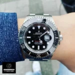 Wrist shot of man wearing 43mm timepiece with black dial and red text, styled after Sea-Dweller design