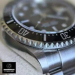 Detail of 43mm Rolex Sea-Dweller's black Cerachrom bezel with engraved numerals and Oystersteel edge