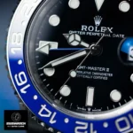 Macro view of the blue‑black bezel meeting the black dial on the Rolex GMT‑Master II 126710BLNR super clone, featuring the red GMT triangle and date Cyclops.