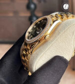 Side profile of the Rolex Day-Date 36 model 128348RBR, showing the diamond-set bezel, case contour, and signature screw-down crown in yellow gold.