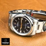 Styled desk presentation of the Oyster Perpetual 36 blue-dial watch showing scale and everyday elegance.