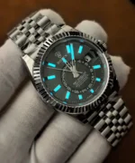 Rolex Sky-Dweller 336934-0002 photographed in darkness, showing blue luminous hour markers and hands against the green dial.