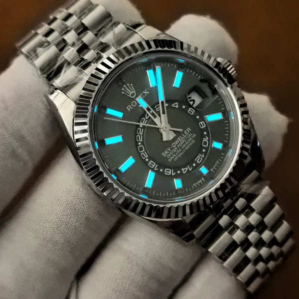 Rolex Sky-Dweller 336934-0002 photographed in darkness, showing blue luminous hour markers and hands against the green dial.